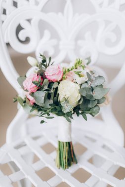 Sandalyesinde pembe ve beyaz güller olan düğün buketi.