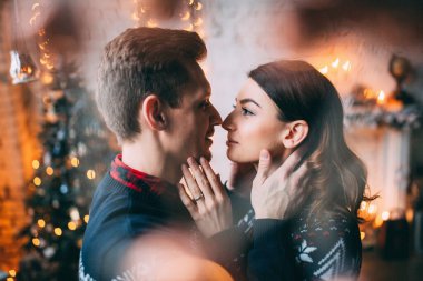 Genç ve güzel bir çift Noel 'de evde birbirlerine sarılıyorlar.                      