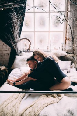 Genç ve güzel bir çift romantik bir evde, yatakta mutlu bir anın tadını çıkarıyor..