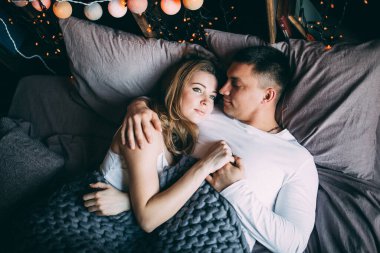 Genç çift yatakta uzanıyor ve sıcak yatak odasında sarılıyorlar. 