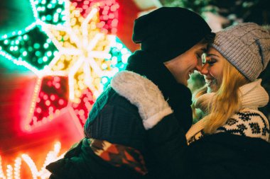 Genç çift, şehirdeki Noel süslerinde kışlık kıyafetler giyiyor. Yeni yılın aşk hikayesi.. 