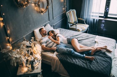 Genç ve güzel bir çift, bir stüdyo odasında yatakta poz veriyorlar.