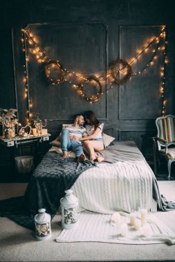 Mutlu çift stüdyoda yatakta poz veriyor. 