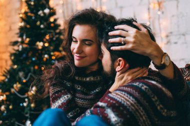 Noel ağacının yanında poz veren genç ve güzel bir çift. 