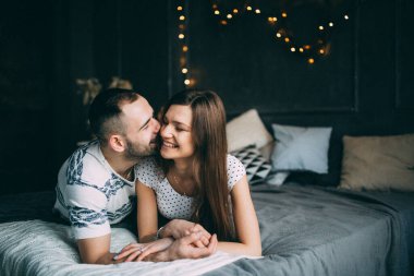 Genç aşık çift stüdyoda yatakta uzanıyor, kapalı bir fotoğraf çekimi. 