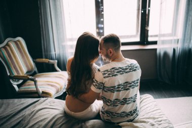 Genç ve güzel bir çift, bir stüdyo odasında yatakta poz veriyorlar.