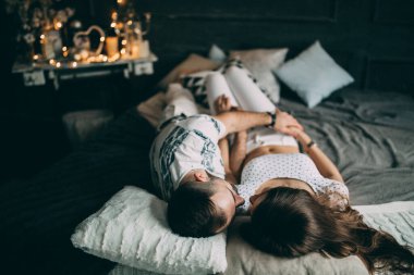 Genç çift, stüdyoda yatakta yalan söylüyor ve sarılıyorlar. 