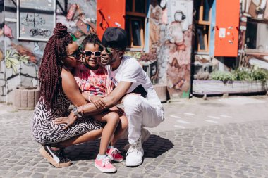 Annesi, babası ve kızıyla sokakta poz veren Afrikalı bir aile.