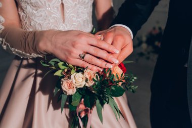 Damat ve gelin elleri bir buketle 