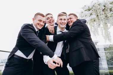 Bir grup arkadaşıyla düğün gününü kutlayan yakışıklı, mutlu genç damat.     