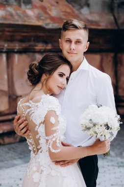 Mutlu genç bir çift yeni evliler kucaklaşıp poz veriyorlar.