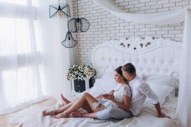 Güzel, genç ve mutlu bir çift yatak odasında birlikte oturuyor.              