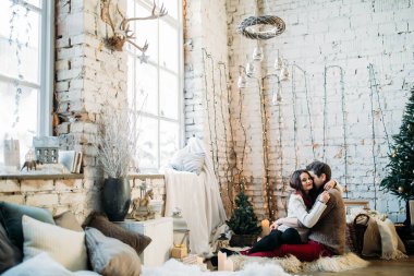 Genç çift oturup fotoğraf çekiminde poz veriyor. 