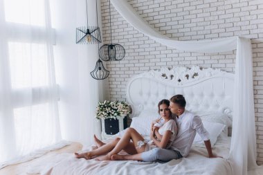 Güzel, genç ve mutlu bir çift yatak odasında birlikte oturuyor.              