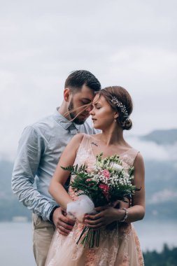 Gelin ve damat dağlarda düğün günlerinde kucaklaşıyorlar.