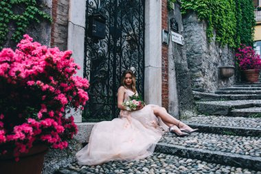 Dışarıda poz veren bir buket çiçekle güzel sarışın gelin. 