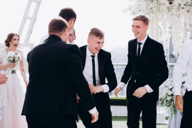 Bir grup arkadaşıyla düğün gününü kutlayan yakışıklı, mutlu genç damat.     