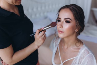 Makyaj sanatçısı sabah genç geline makyaj yapıyor. 