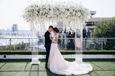 Çiçeklerle balkonda poz veren çift.