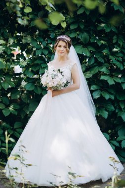 Gelinlikli güzel gelinin portresi Parkta bir buket çiçek tutuyor            