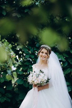 Gelinlikli güzel gelinin portresi Parkta bir buket çiçek tutuyor            