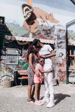 Annesi, babası ve kızıyla sokakta poz veren Afrikalı bir aile.