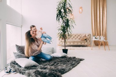 Mutlu anne ve kız yerde oynuyorlar.