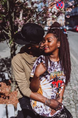 Afrikalı çift sokakta öpüşüyor ve sarılıyor.