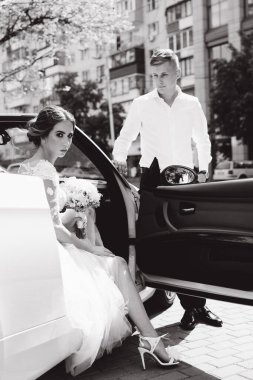 Şehirde lüks arabası olan zarif genç bir çiftin siyah beyaz görüntüsü.