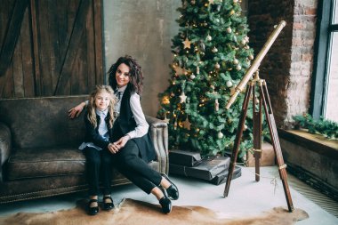 Mutlu anne ve küçük kızı Noel için dekore edilmiş stüdyoda poz veriyorlar.