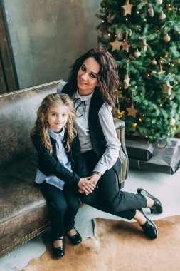 Mutlu anne ve küçük kızı Noel için dekore edilmiş stüdyoda poz veriyorlar.