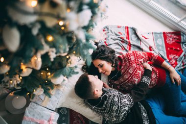 Mutlu genç çift, yataklarında rahat bir odada Noel süslemeleriyle  