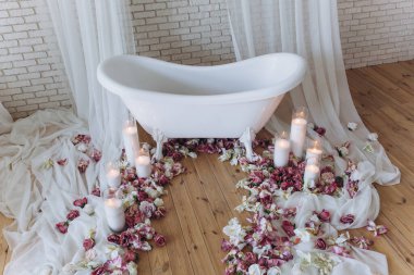 Banyoda çiçekler ve mumlarla dolu güzel beyaz bir küvet.               