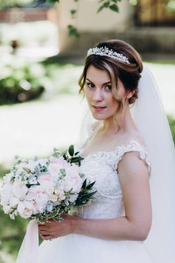 Gelinlikli güzel gelinin portresi Parkta bir buket çiçek tutuyor            