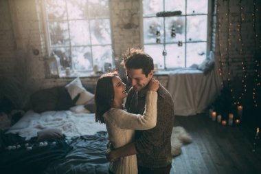 Güzel, mutlu, birbirine aşık genç bir çift sıcak bir odada kucaklaşıyorlar..                   