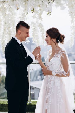 Gelin ve damat çifti ellerinde şampanya kadehleriyle birbirlerine gülümsüyorlar.