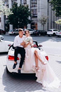Yakışıklı damadı beyaz arabasında oturan güzel genç gelin.  