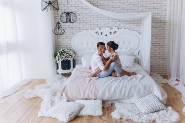 Güzel, genç ve mutlu bir çift yatak odasında birlikte oturuyor.              