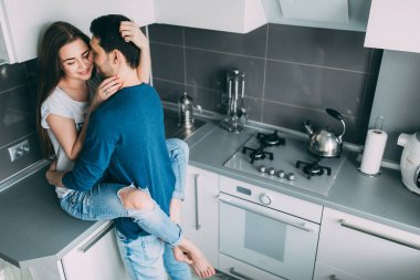 Yüksek açılı, birbirine aşık genç bir çiftin mutfakta kucaklaşması.