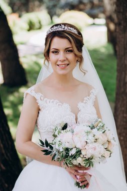 Gelinlikli güzel gelinin portresi Parkta bir buket çiçek tutuyor            