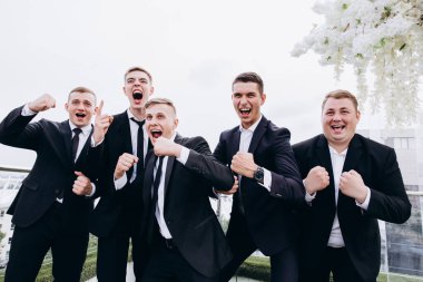 Bir grup arkadaşıyla düğün gününü kutlayan yakışıklı, mutlu genç damat.     