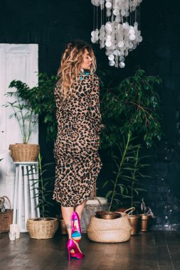 Stüdyoda poz veren şık leopar desenli elbiseli güzel bir kadın.