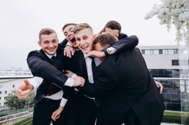 Bir grup arkadaşıyla düğün gününü kutlayan yakışıklı, mutlu genç damat.     