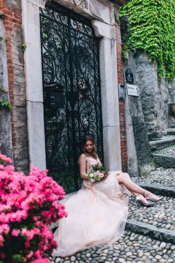 Dışarıda poz veren bir buket çiçekle güzel sarışın gelin. 