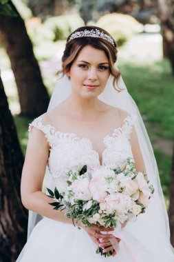 Gelinlikli güzel gelinin portresi Parkta bir buket çiçek tutuyor            