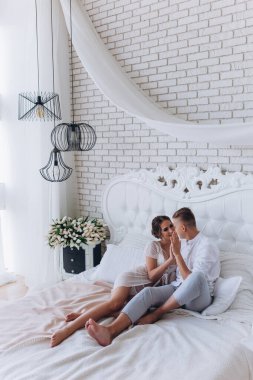 Güzel, genç ve mutlu bir çift yatak odasında birlikte oturuyor.              