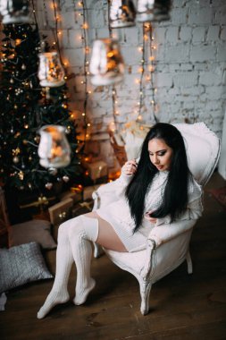 Stüdyonun içinde beyaz kazak giyen güzel, genç seksi kadın poz veriyor.