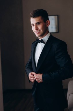 Yakışıklı genç damat portresi. Düğün gününde şık siyah takım elbise ve papyon takıyor.        