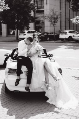 Şehirde arabada oturan bir çiftin siyah beyaz görüntüsü.