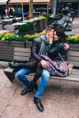 Genç ve güzel bir çift öpüşüyor ve bankta birlikte oturuyorlar. 